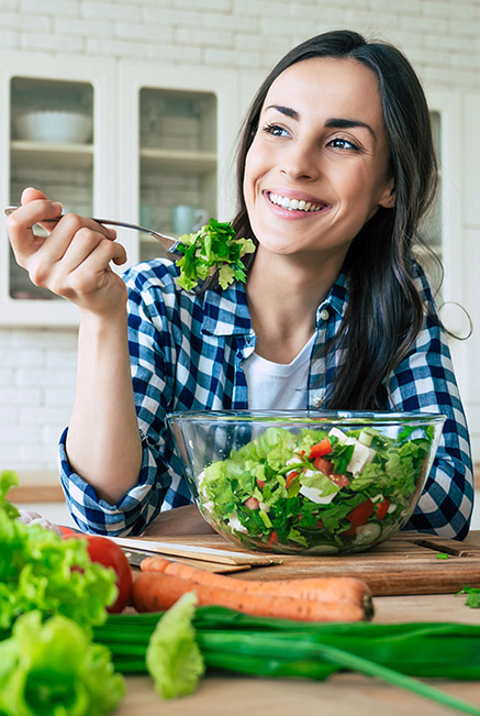 a woman eating a healthy salad to lower body fat