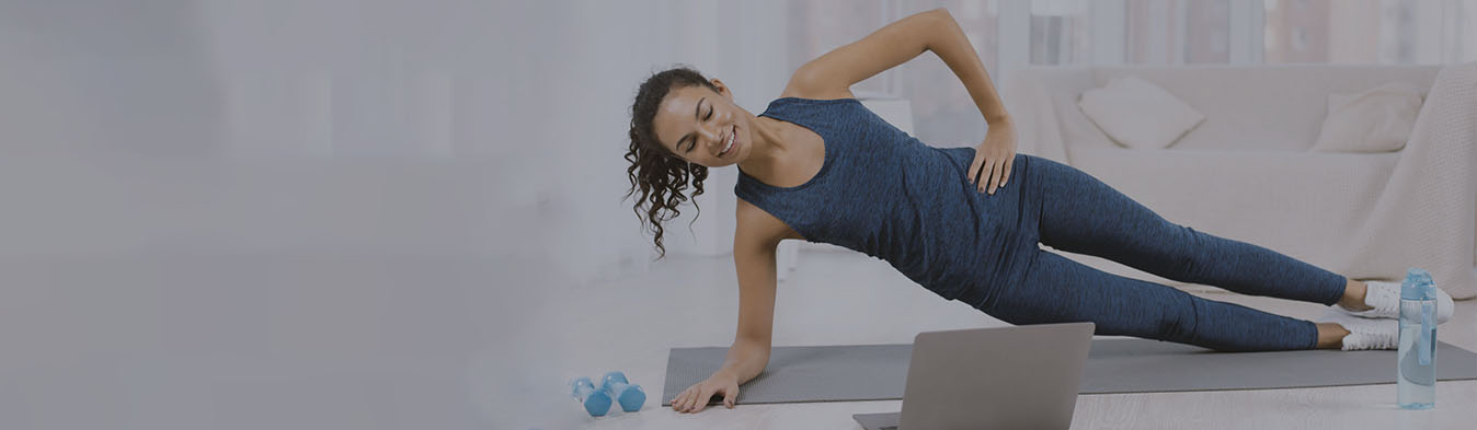 Woman doing a side plank while looking at laptop
