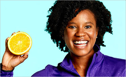 a smiling woman holding an orange